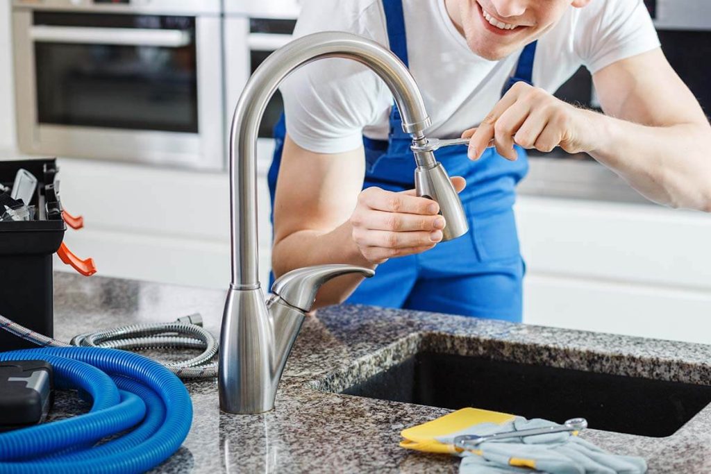 plumber fixing kitchen faucet