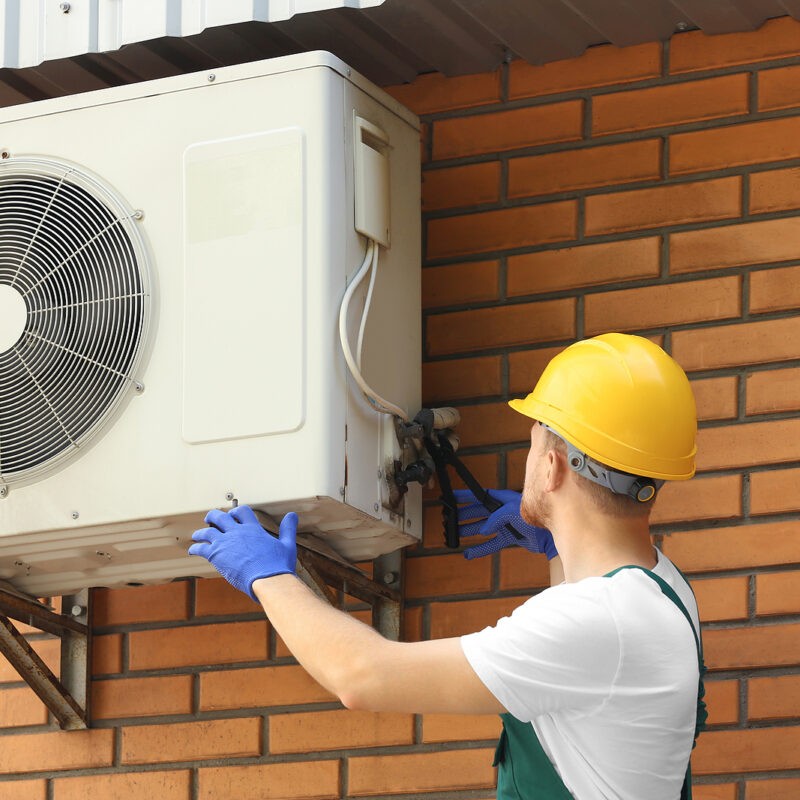 Professional-HVAC-Technician-Repairing-Repairing-Wall-Mounted-Air-Conditioner-Outdoors